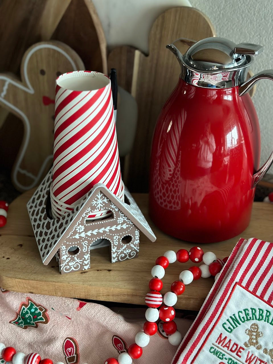 Cup Holder with Party Decorations – The gingerbread house cup holder displayed alongside Christmas-themed party decorations and a hot cocoa bar setup.