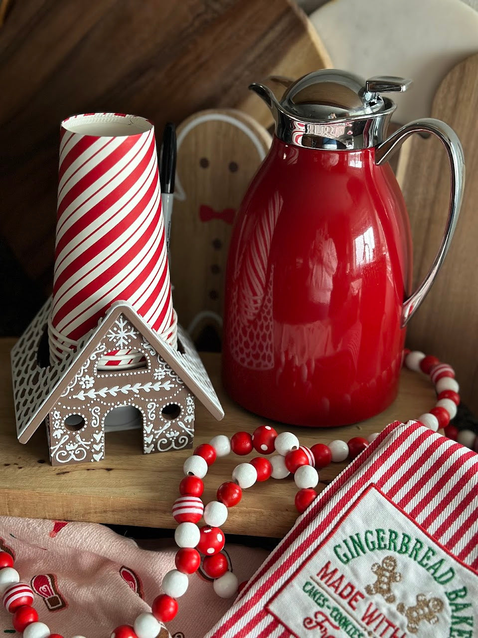 Cup Holder with Party Decorations – The gingerbread house cup holder displayed alongside Christmas-themed party decorations and a hot cocoa bar setup.