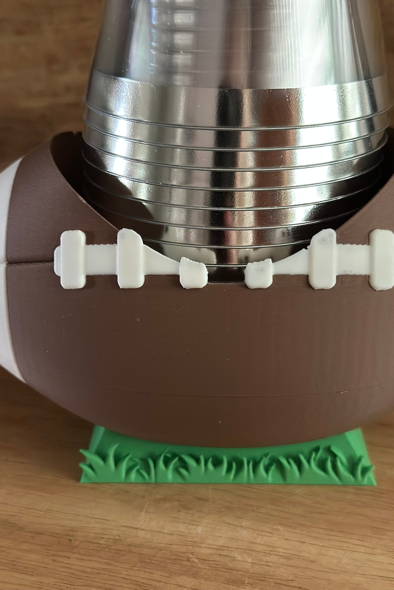 Football-shaped cup holder with a metallic base on a wooden surface