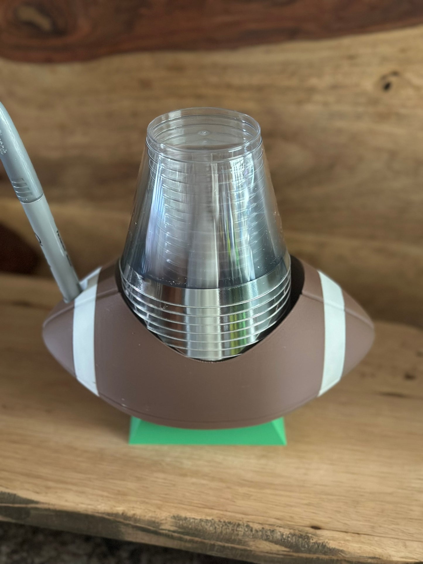 Football-shaped cup holder with clear cups on a wooden surface
