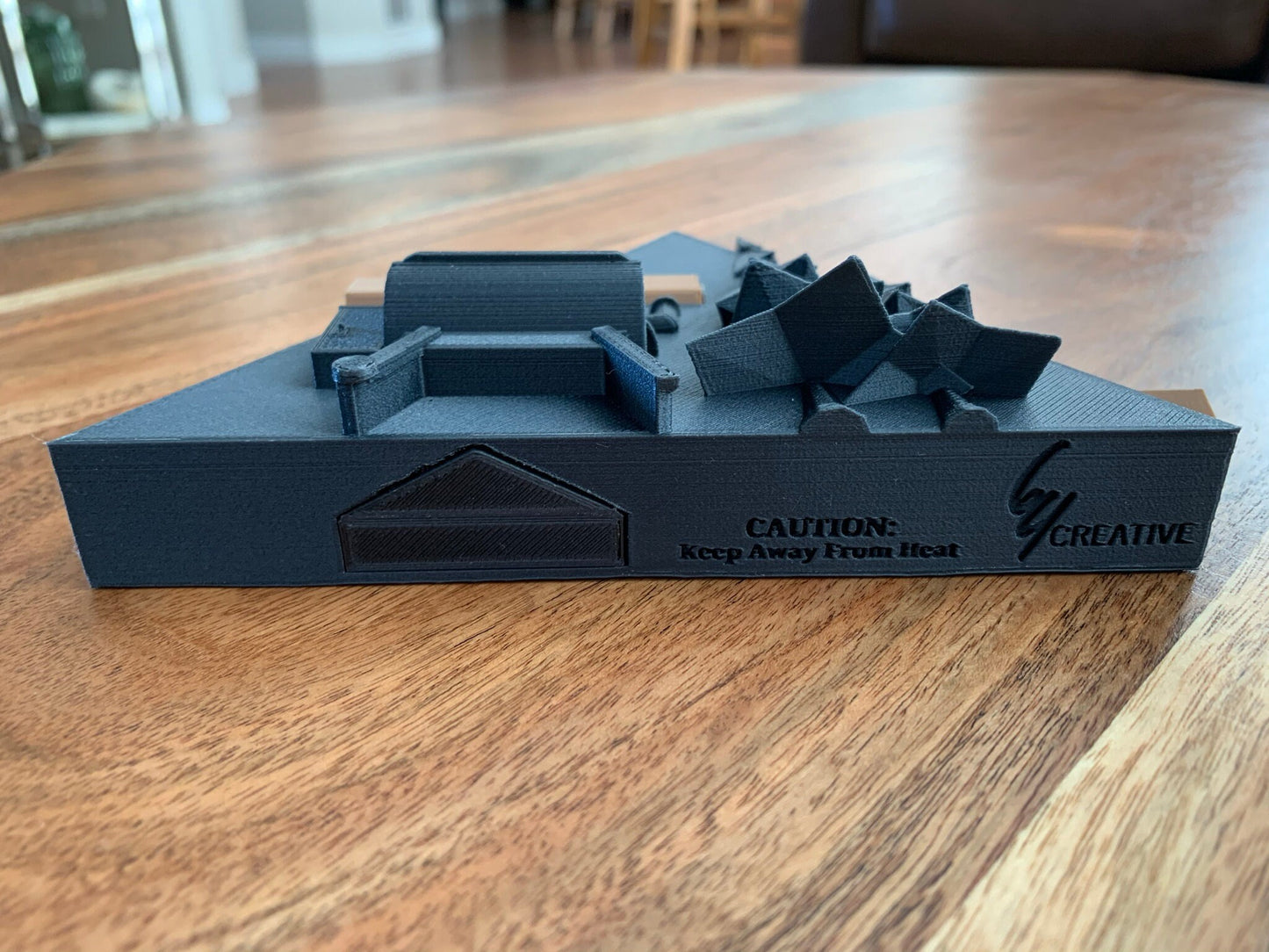 Close-up of a 3D printed pellet label magnet with detailed mountain design and hidden magnets inside the log for secure attachment laying on it's back.
