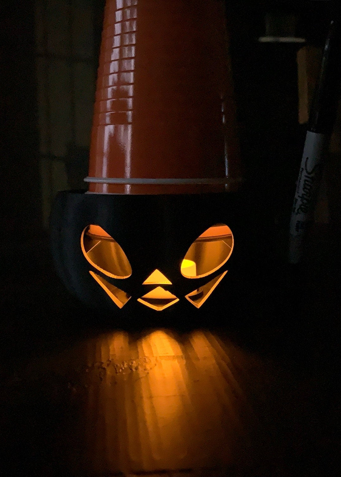 Night profile of the Pumpkin Party Cup Holder illuminated by its LED tea light, showcasing its jack lantern design.