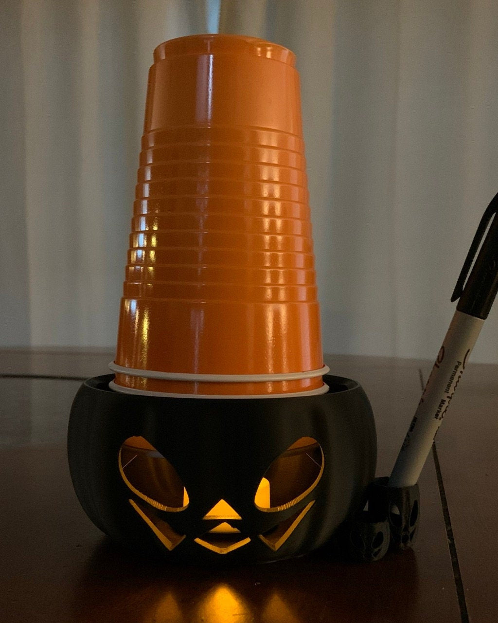 Dark Night time view of the Pumpkin Party Cup Holder highlighting its sturdy build and functional design for party tableware decor. The Tea light illuminates the jack o lantern effect.