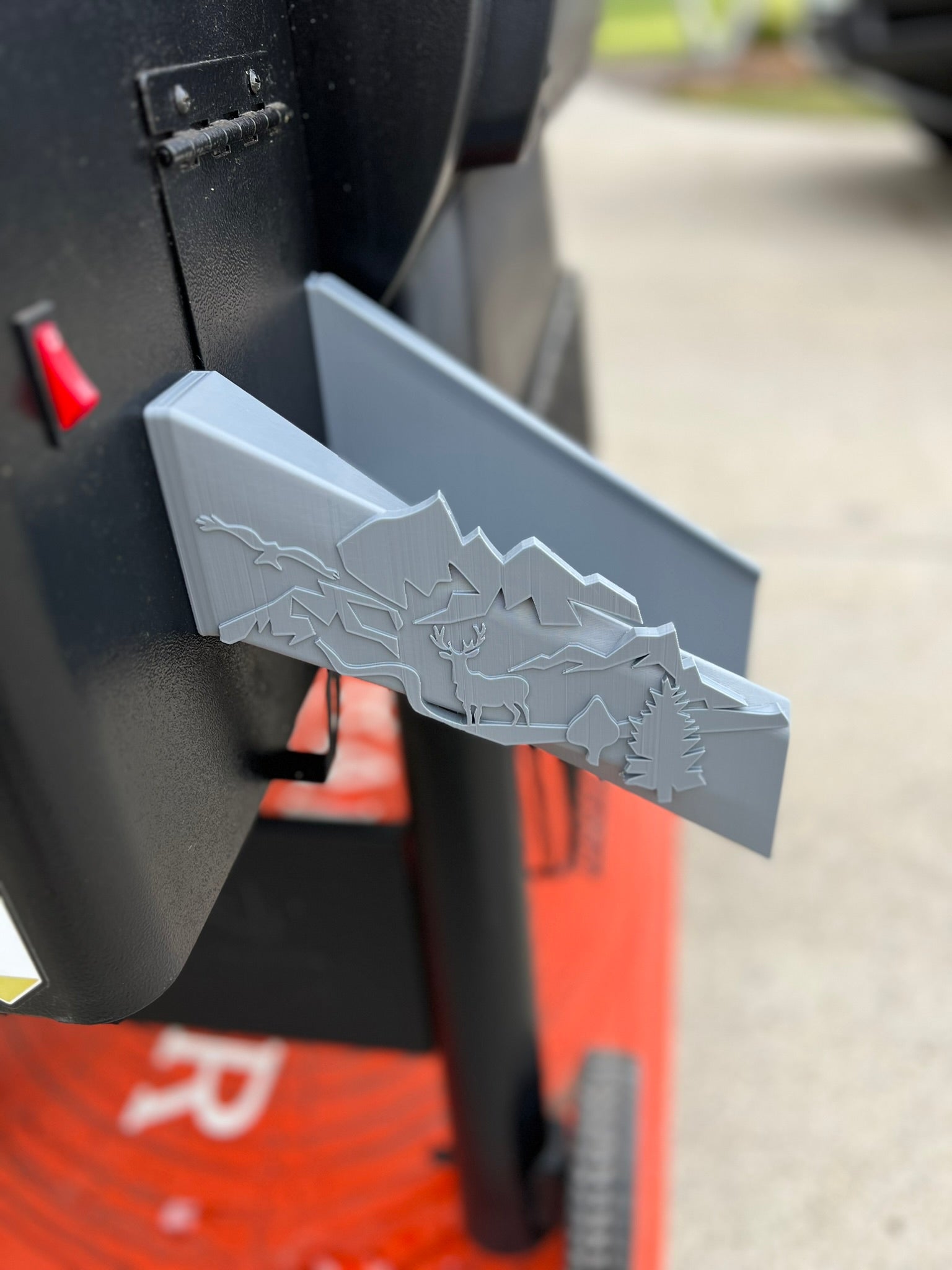 Pellet chute accessory for Traeger grill with nature-inspired deer and forest accents for easy pellet discharge.