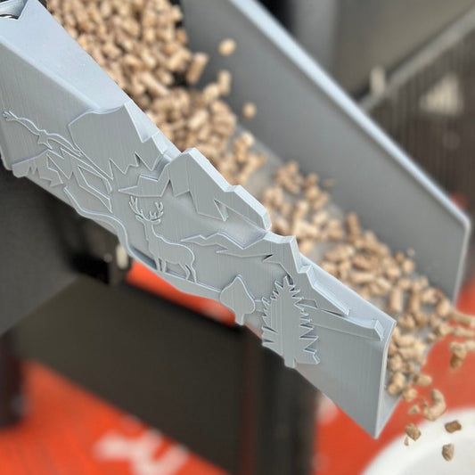 Close-up of plastic pellet chute for Traeger grill featuring deer, forest, and nature-inspired accents.