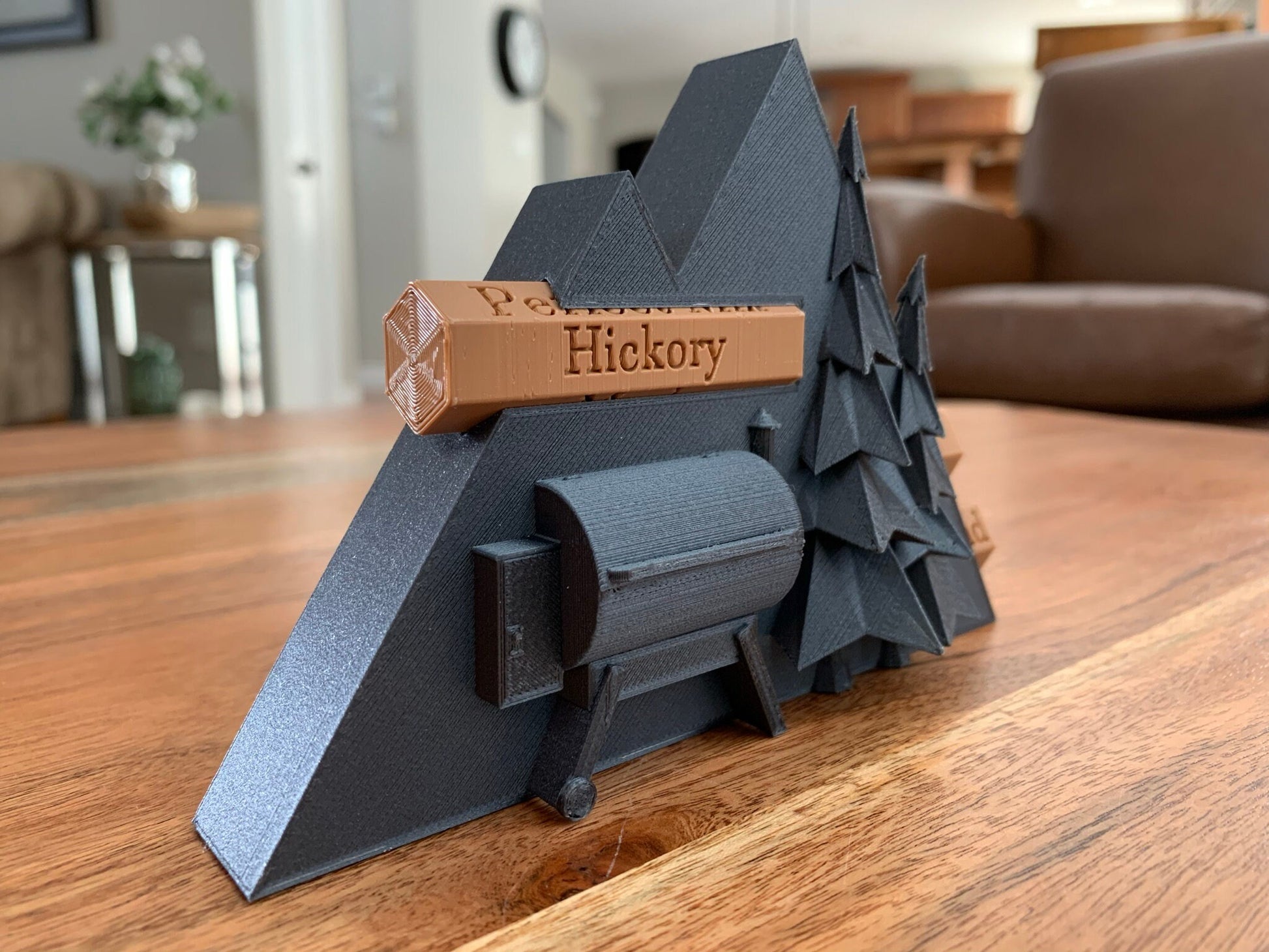 Close-up of a 3D printed pellet label magnet with detailed mountain design and hidden magnets inside the log for secure attachment.
